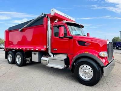 A red dump truck is parked on a paved surface, exuding strength and reliability, under a clear blue sky that stretches endlessly above.