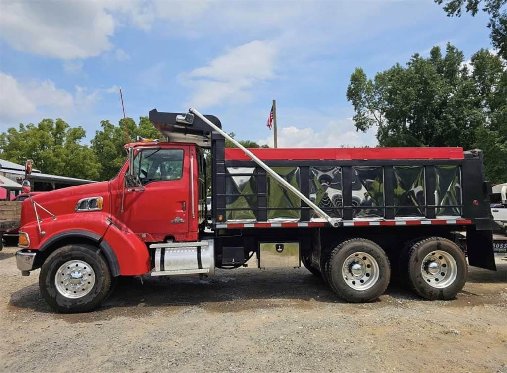 A red and black dump truck, representing top-notch services, is parked on gravel with trees in the background.